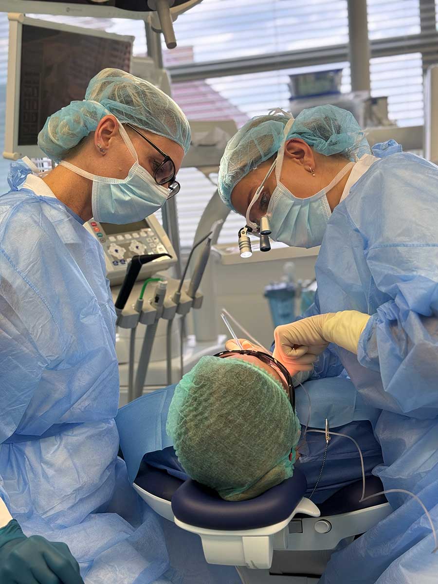 Lekarz i asysta podczas zabiegu chirurgicznego przy unicie stomatologicznym